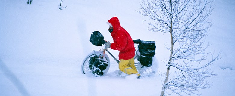 Bild på person som leder cykel i snö